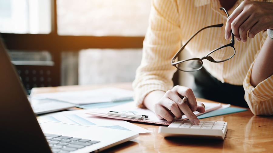 woman holding glasses working on a calculator