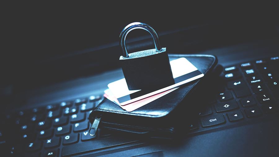 Padlock sitting on top of credit cards and a wallet. This is all on top of a laptop keyboard