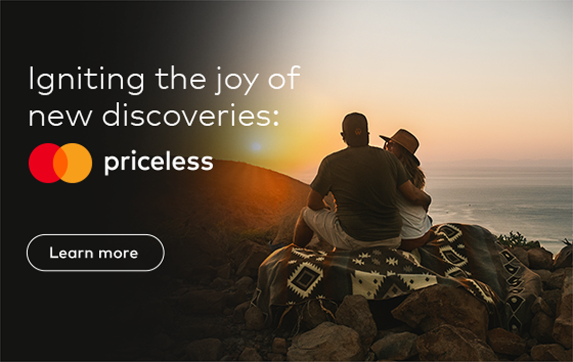 Photo of a couple sitting on the hilltop facing the sunset overlooking the next hilltop.  Text Overlay saysZ: Igniting the joy of new discoveries: Priceless. Mastercard logo, button which reads: Learn more.