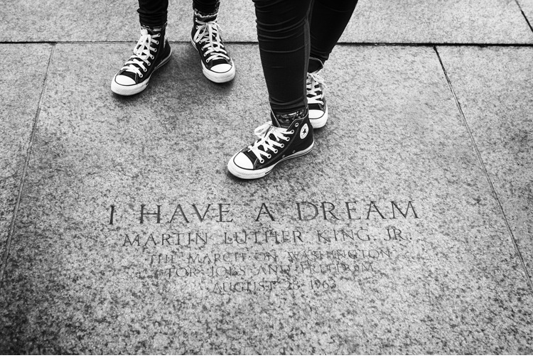 image of two people's feet wearing high top Converse tennis shoes on the engraved pavement 